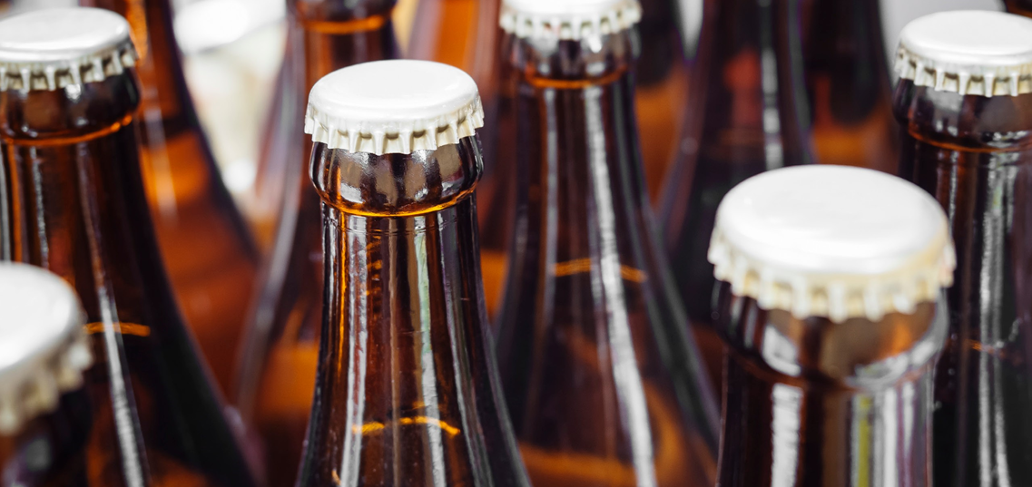 Close up of the tops of multiple beer bottles