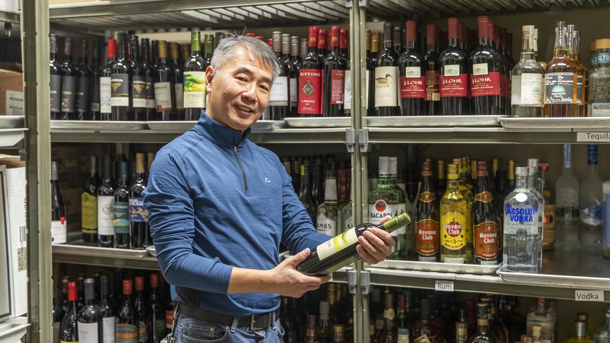 Employé de la CAJO tenant une bouteille de vin dans un magasin d'alcools.