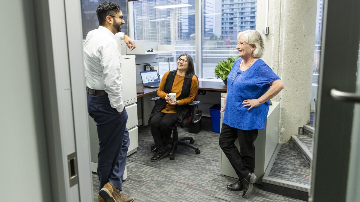 Trois employés de la CAJO discutent pendant une pause dans le couloir.