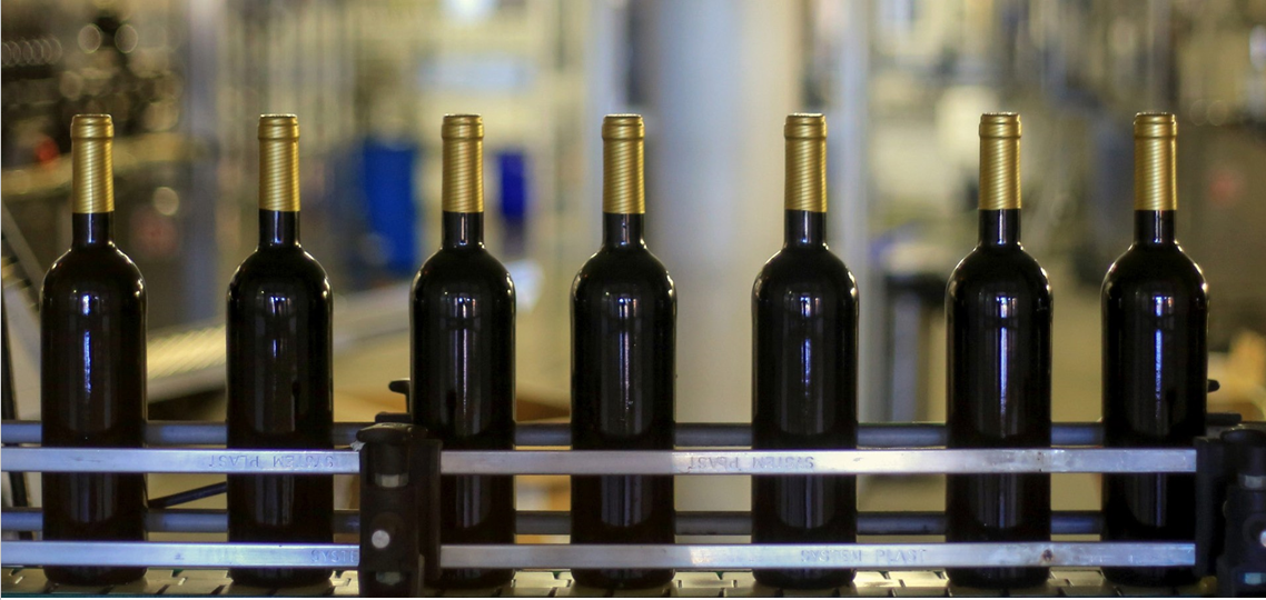 Seven bottles of red wine upright in a horizonal line